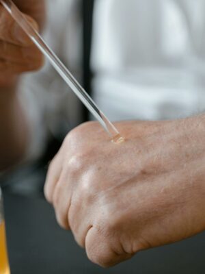 Close-up of a person applying perfume on their hand with a dropper, showcasing the art of fragrance testing.